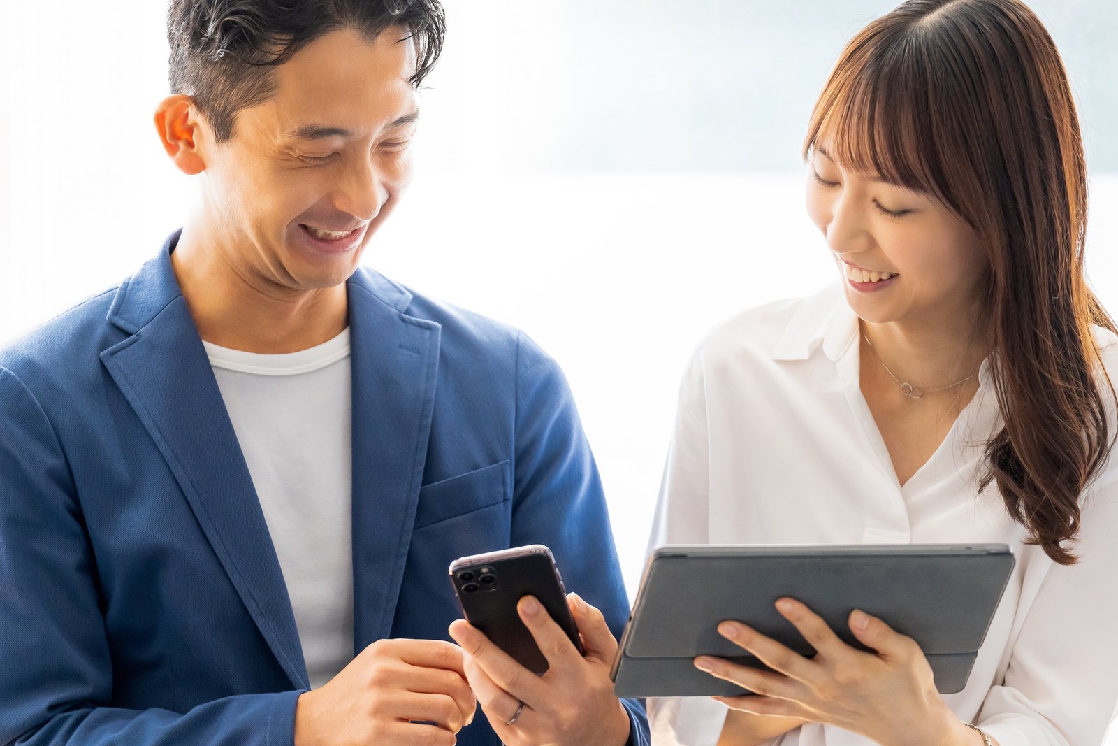 スマートフォンとタブレットで販売状況を確認する担当者